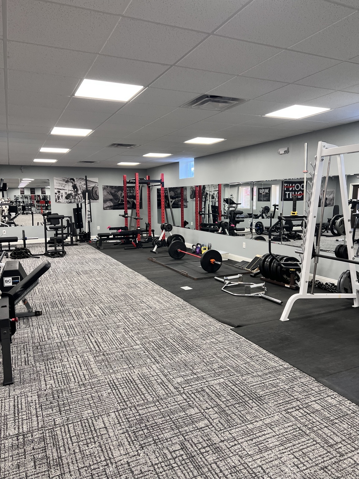 The Wolf Den Strength and Fitness gym floor with racks, barbells, benches, and free weights